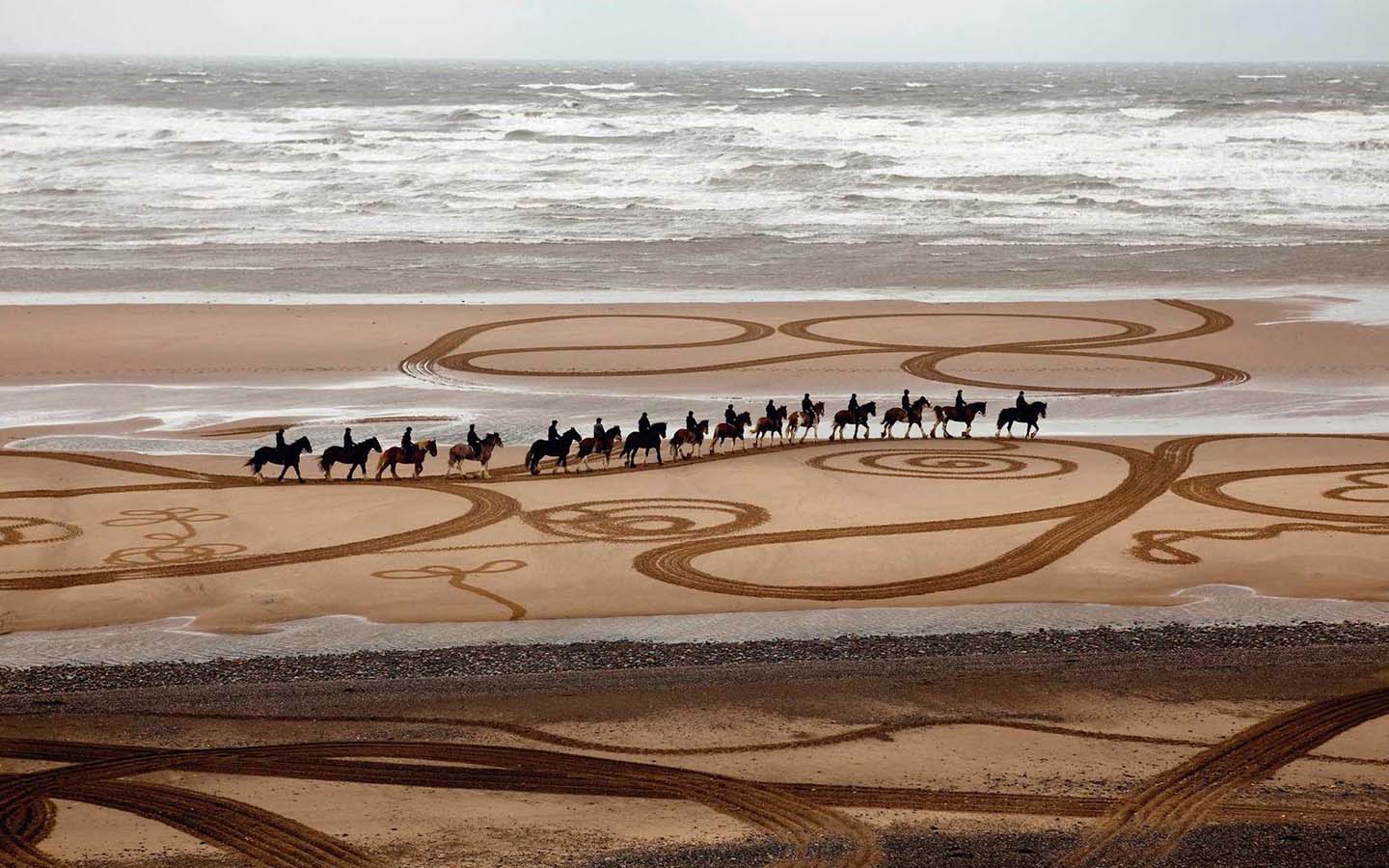 Artwork of horses with riders along the beach by Eve Wright